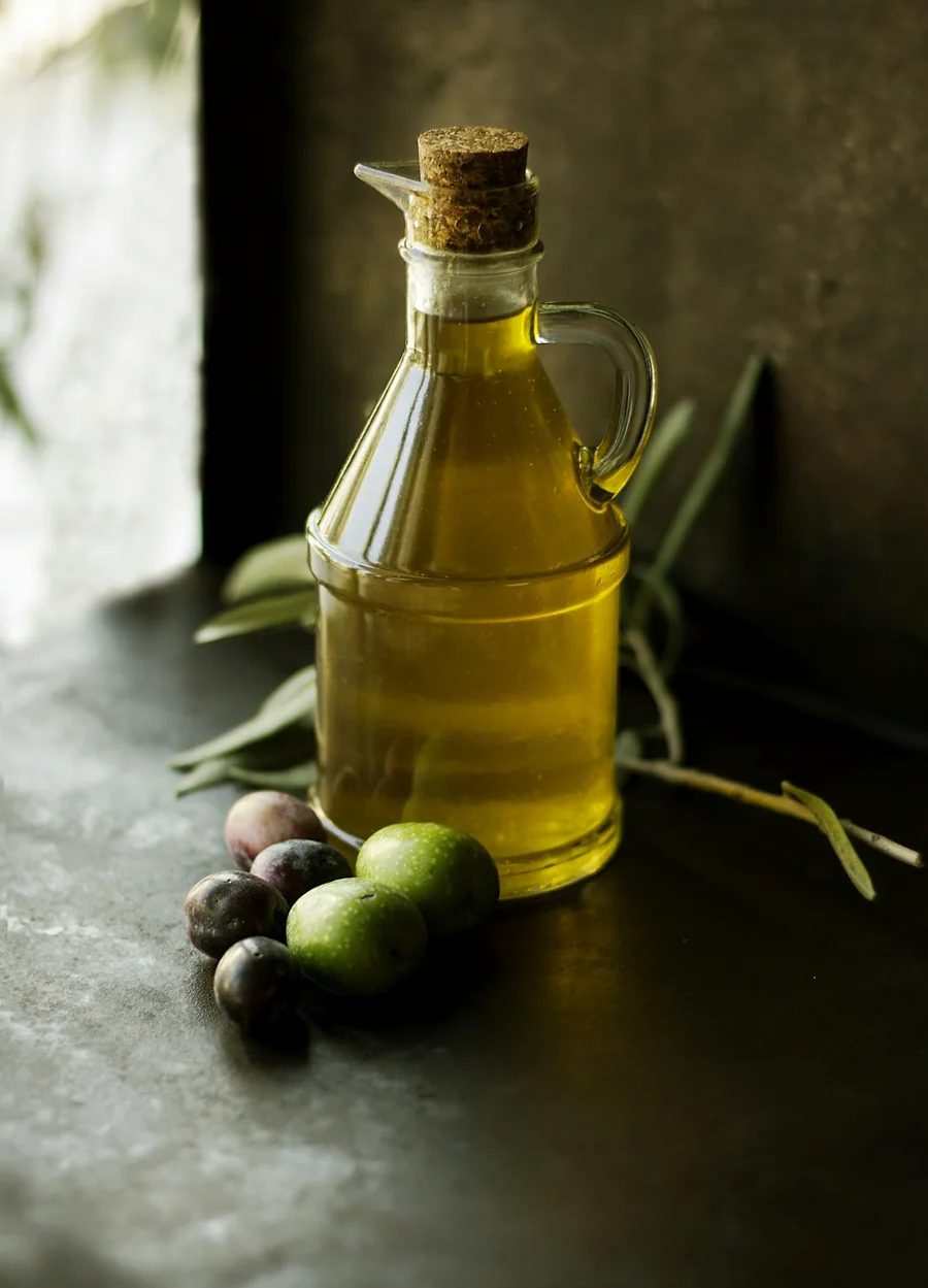Aceite de oliva en una botella, con aceitunas y hojas