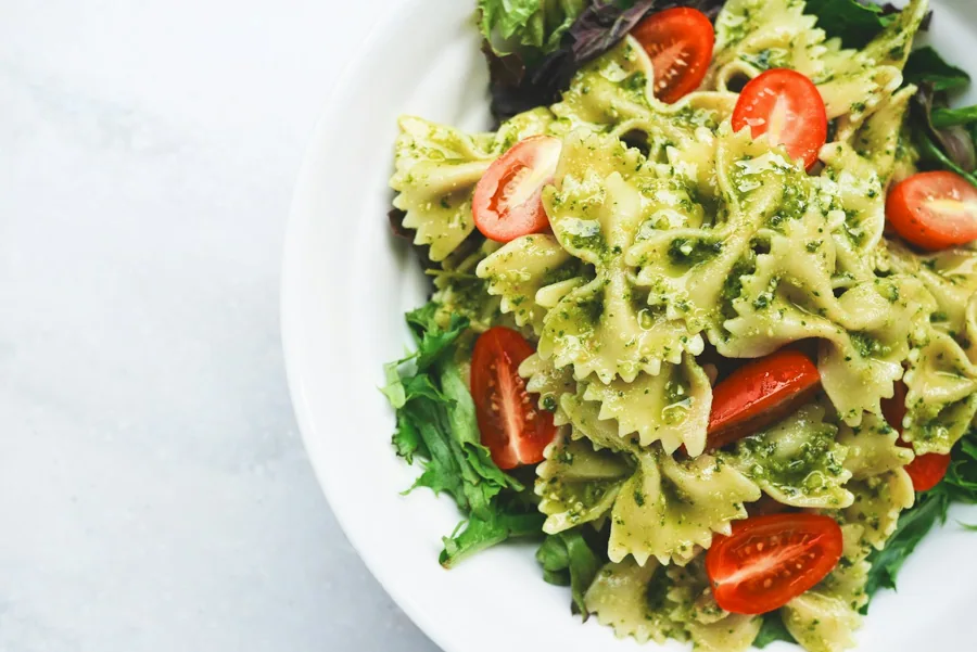 Pasta con pesto, tomates y hojas de albahaca