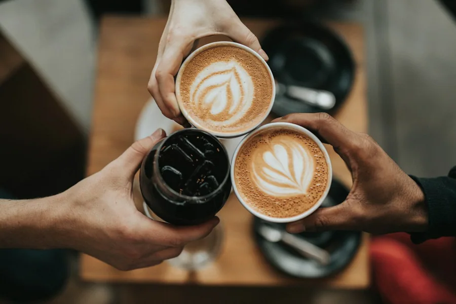 Varias tazas de café con leche sostenidas con las manos